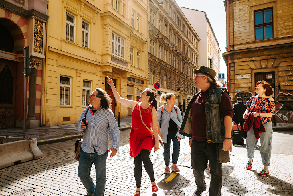 a group of tourists lead by a tourist guide through the streets of Prague