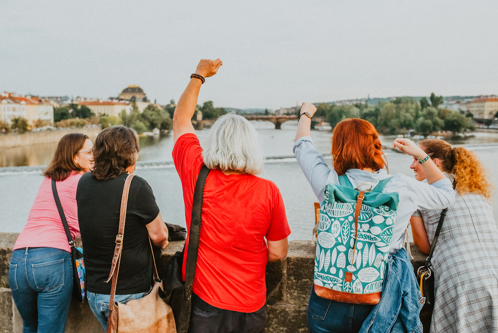 a group of happy tourists and a tour guide standing on the Charles Bridge in Prague enjoying their worry-free vacation in the city