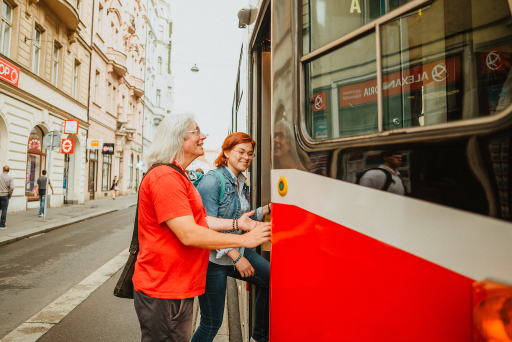 a tourist getting on a tram in Prague with the help of a friendly tour guide