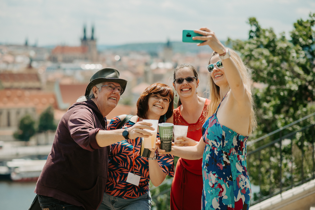 a happy group of tourists in Prague taking a selfie with an amazing view of the city in the background