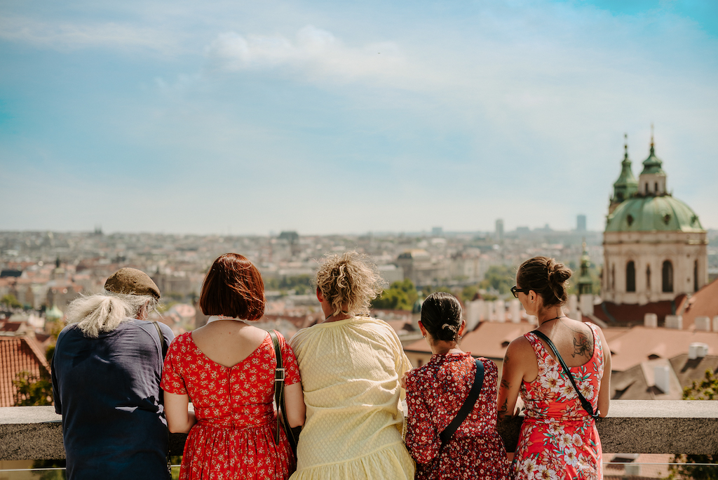 a group of people standing close together admiring a beautiful panoramic view of Prague