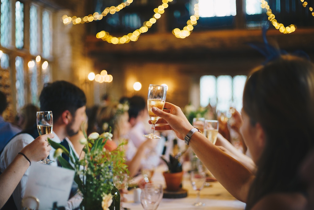 a group of people sitting at a table in a fancy restaurant raising a glass of champagne to toast