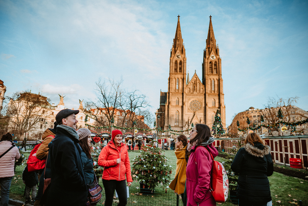 a group of tourists with a tour guide exploring the Christmas Markets on Namesti Miru in Prague