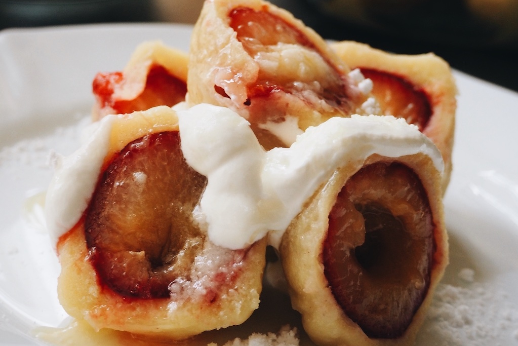 a close up of plate of authentic Czech fruit dumplings filled with plums and topped with cottage cheese