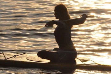 a woman on a paddle board at sunset