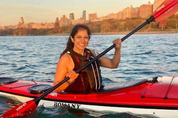 a woman in a red Romany sea kayak on the Hudson River in NYC