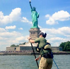 a man riding a paddle board at the Statue of Liberty