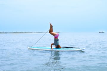a girl doing a headstand on a paddleboard