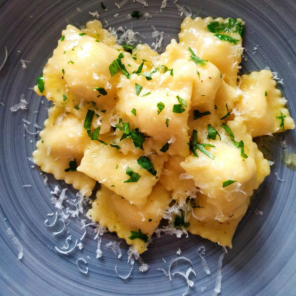 a close up of a plate of ravioli with butter and parmesan cheese