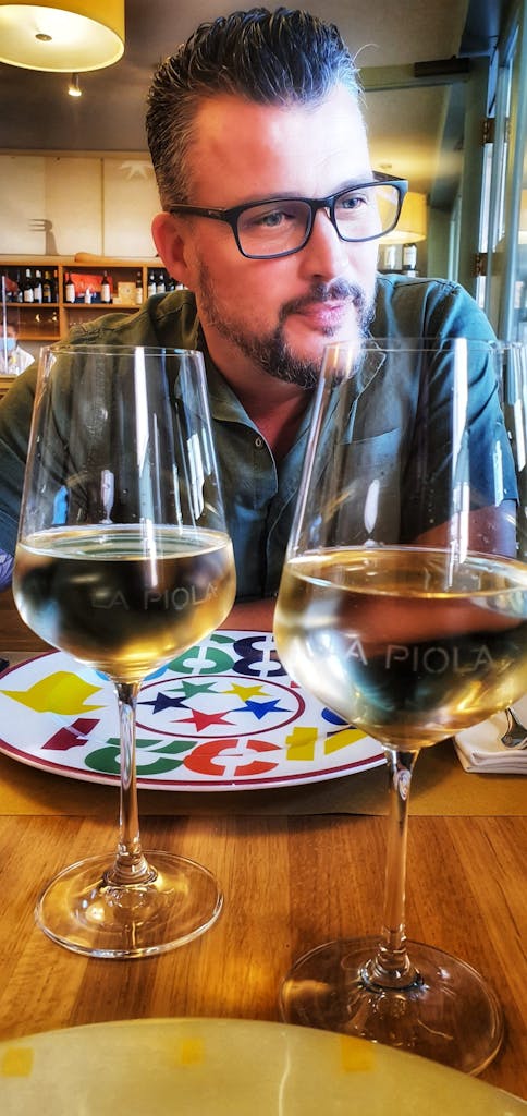 a man sitting at a table with wine glasses