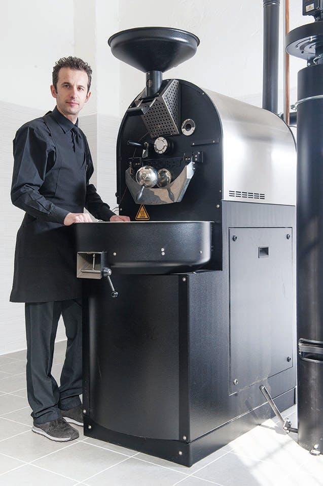 a man standing in front of a coffee roaster