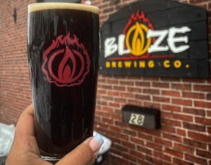 A Maine Stout in a glass held in front of Blaze Brewing