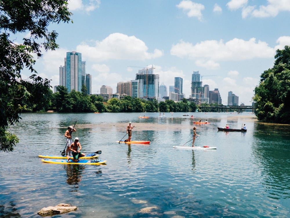 a group of people rowing a boat in a body of water with Chapultepec in the background