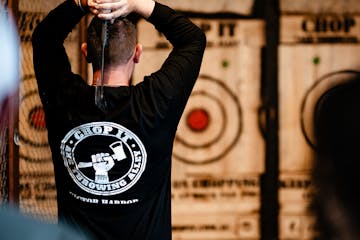 man in black tshirt throws axe at target