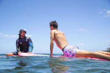 Man teaching boy to surf on water