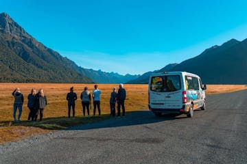 a group of people standing in front of a mountain road