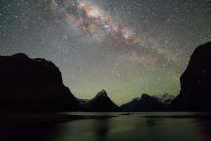 a body of water with a mountain in the dark