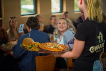 a group of people standing around a table eating pizza