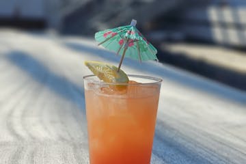 A glass of Dan Seavey's Best Punch with an umbrella on the deck of Tall Ship Windy