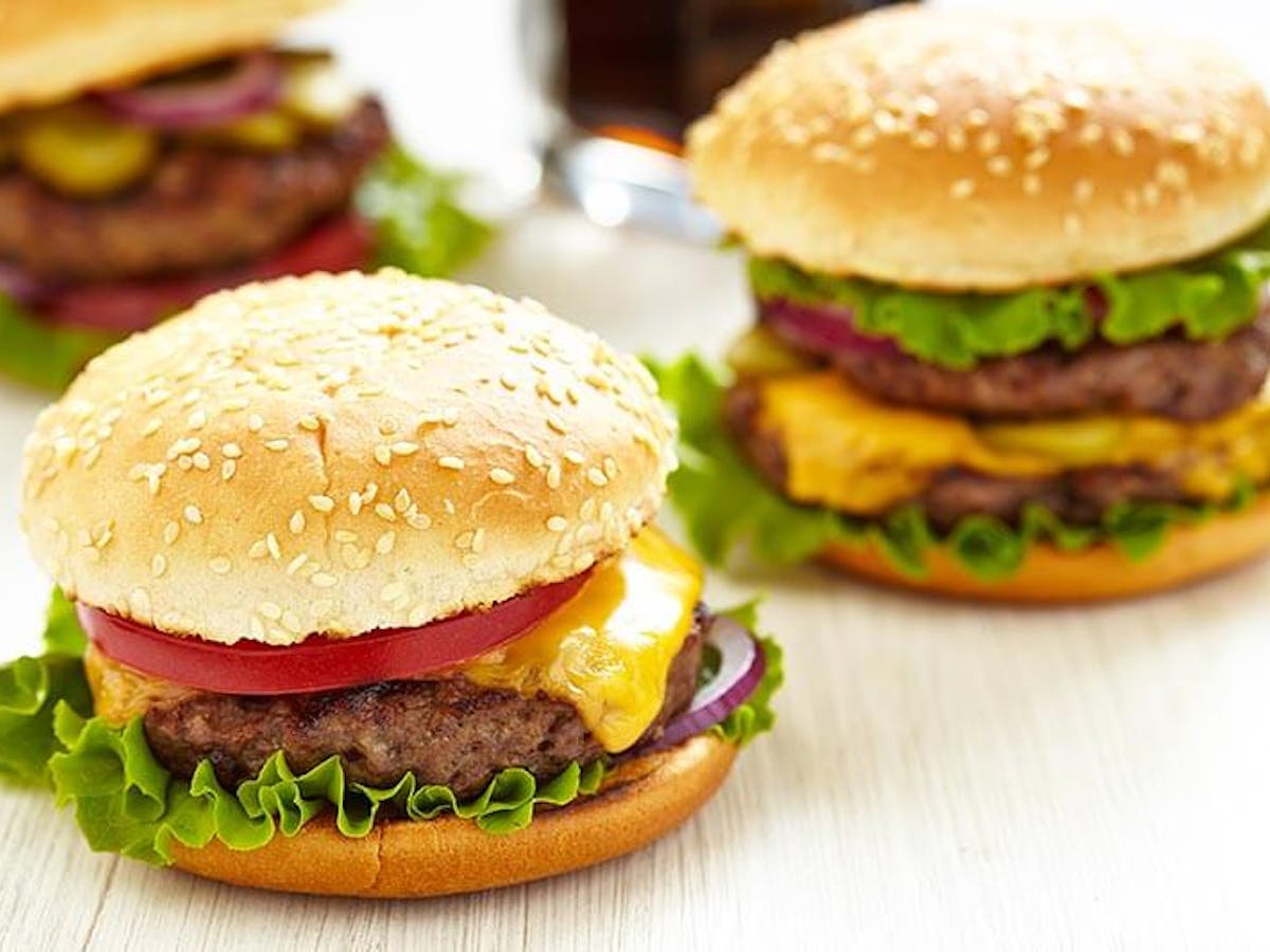 close up of two cheeseburgers with lettuce and tomato