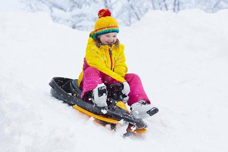Child riding a sled in snow