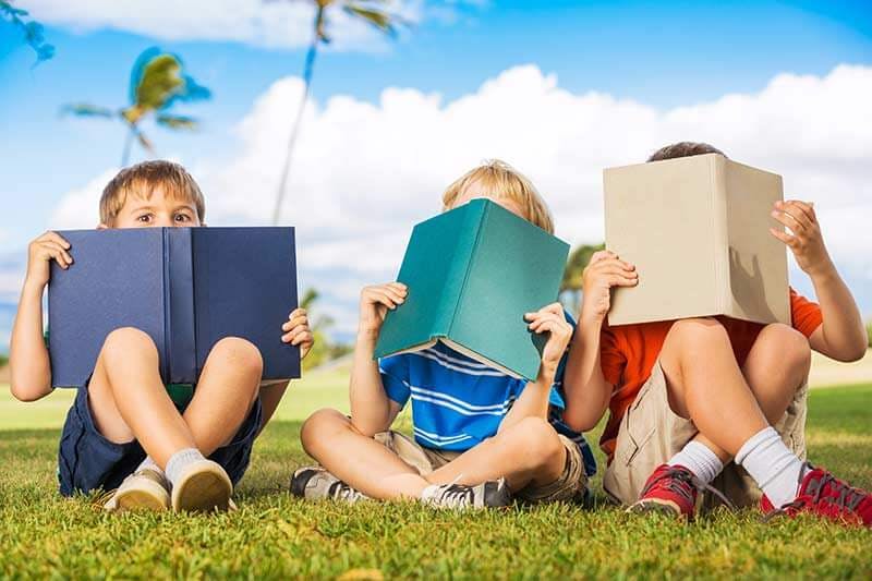 Three kids reading for International Children's Book Day