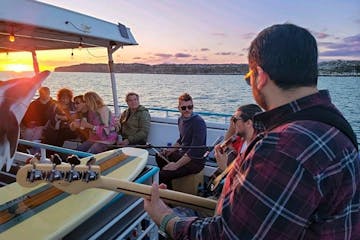 Passengers listen to live music during sunset harbor cruise on Hoku Nai'a