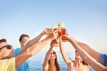 A group of friends toasting with beer near the ocean