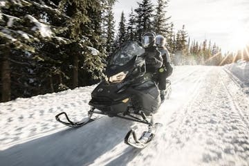 a man riding a motorcycle down a snow covered slope