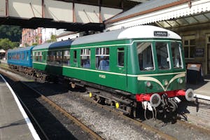 a green train that is sitting on a track