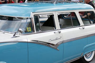 a blue and white boat parked next to a car