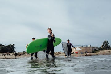 a group of people walking on a beach holding a surf board