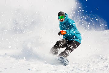 a man flying through the air on a snow covered slope