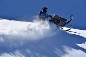 a man flying through the air while riding a snowboard down a snowy hill