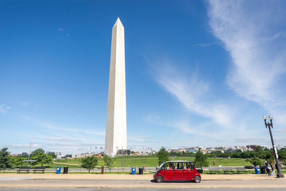 a group of people standing in a parking lot with Washington Monument in the background