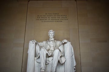 a statue of a person with Lincoln Memorial in the background
