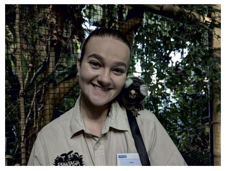 a girl posing for the camera with a monkey on her shoulder