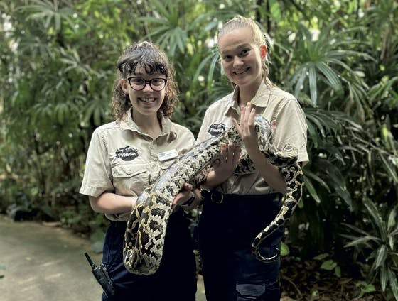 2 girl zookeepers holding a large python