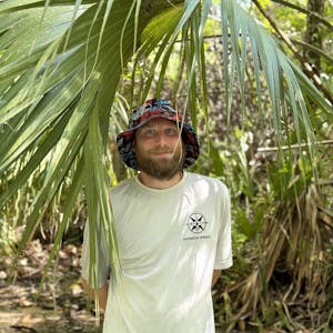 a man standing next to a palm tree