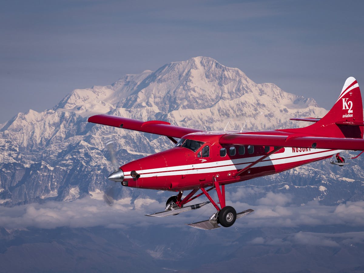 a small plane flying in front of mount Denali