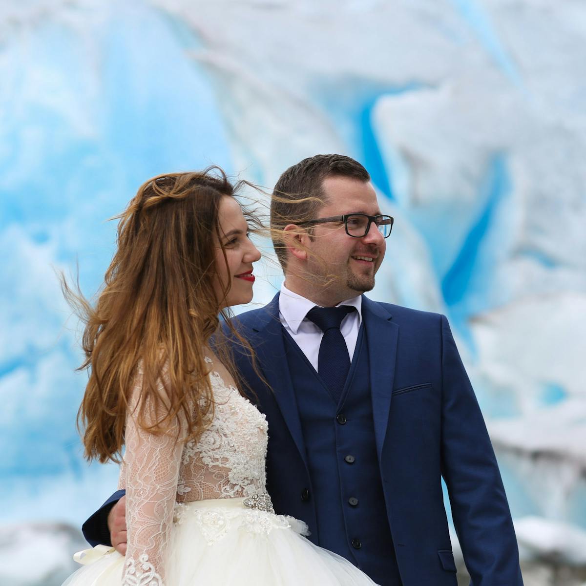 a bride and groom posing on a glacier