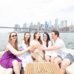 friends drinking champagne by the Brooklyn Bridge on a boat rental in NYC