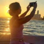woman taking a picture of the sunset during a nyc cruise