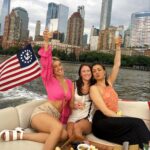 friends on a private party yacht in New York City with the skyline and American flag