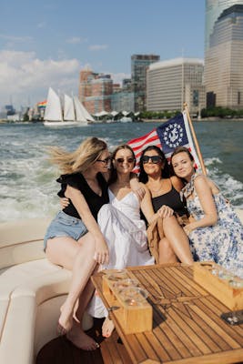 a group of friends on a boat rental NYC party with a sailboat and the financial district in the background