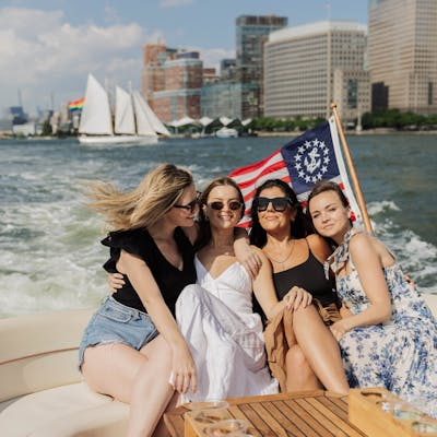 a group of friends on a boat rental NYC party with a sailboat and the financial district in the background