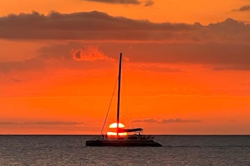 a sunset behind a boat on a body of water