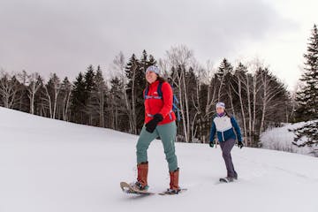 two people snowshoeing along a snow covered slope