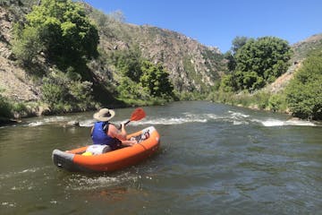 a man kayaking on the river in an inflatable kayak