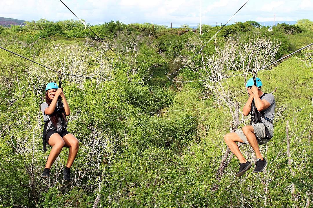 Two people ziplining side by side at Coral Crater